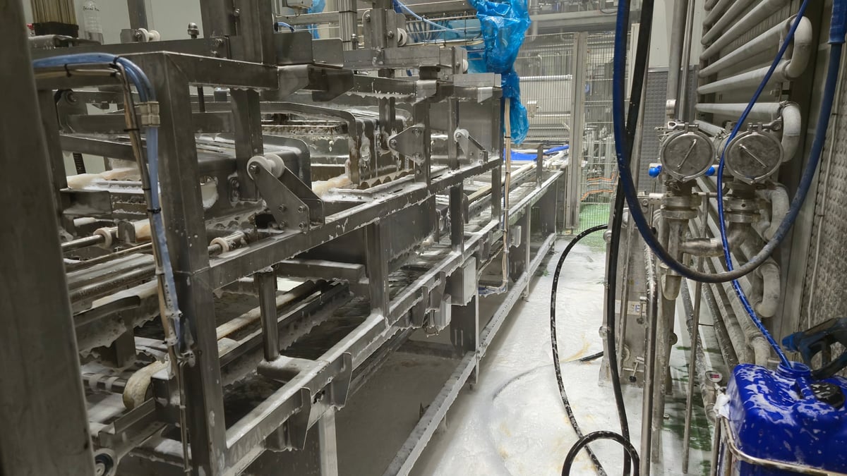 Línea de producción industrial siendo sanitizada con detergente especializado