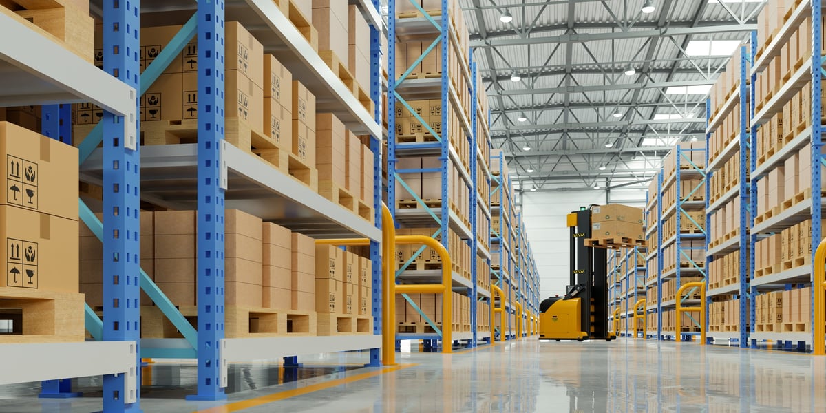 Interior de un almacén logístico moderno con estanterías altas, tarimas y montacargas para gestión de inventario y envíos industriales