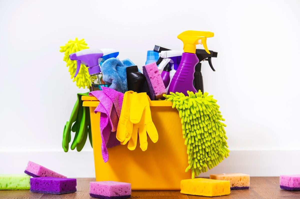 Productos químicos de limpieza de varios colores, botellas, jergas, esponjas y guantes de protección