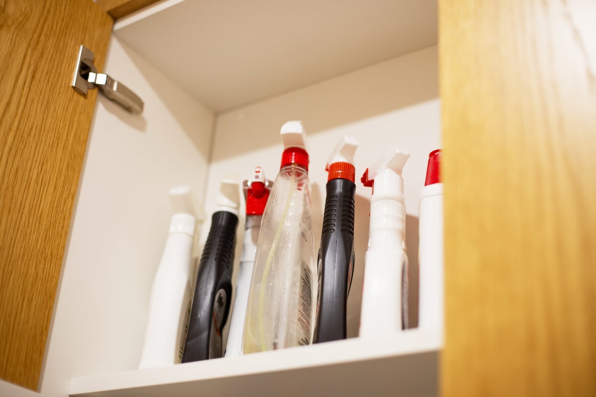 Botellas con atomizador de distintos productos de limpieza organizadas en el estante de un almacén